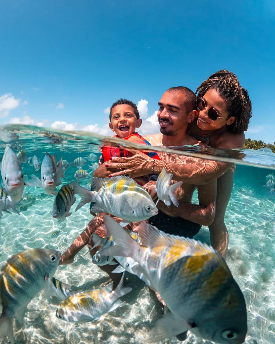 Família em foto meio dentro, meio fora d'água nas piscinas naturais de Morro